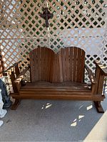 Front view of wooden two-person glider bench showing curved slat backrests and armrests