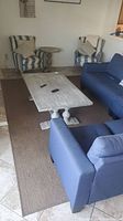 Wide view of large brown area rug set in living room under coffee table and seating furniture showing overall size and color.