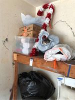 Shelf with multiple Christmas boxes and storage container with ornaments, red and white candy cane garland visible