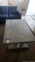 Full view of rectangular faux wood veneer coffee table in front of blue upholstered sofa