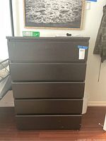 Front view of dark brown wooden highboy dresser with five drawers, showing worn condition.