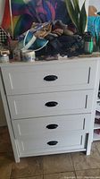 Front view showing four drawers with black handles and items placed on top.