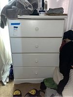 Frontal image of the white four-drawer dresser showing the four drawers and items on top.