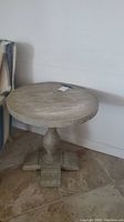Front and side view of the round faux wood veneer occasional table showing pedestal base and wood grain pattern.