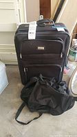 Full view of black rolling suitcase with black bag in front