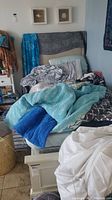 Photo showing the twin bed with upholstered headboard covered with blankets and pillows.