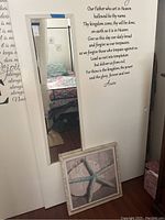 Mirror mounted on wall with print below, showing wall decal text and room reflection