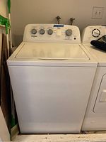 Front view of white Whirlpool top-loading washing machine with control panel and knobs