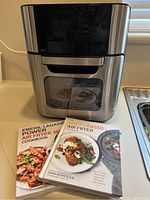 Closed view of Emeril Lagasse Air Fryer 2 with the two cookbooks placed in front.