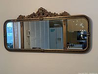 Front view of the large antique wall mirror showing ornate carved wooden frame and reflective glass.