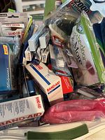 Bucket filled with various bathroom essentials such as Band-Aid boxes, individual toothbrushes, floss, razors, and medical supplies.