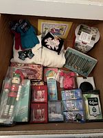 Photo showing assorted gift items including sweatshirt, gloves, candles, nutcracker, plant kit, and various small household and decorative items