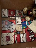 Shows all items together including bracelets, cologne, dog sweater, soap, candleholder, teddy bear, calendars, and stationery.