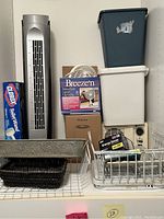 Shelf with household items such as Clorox toilet wand refills, tall tower fan, Breezer humidifier fan box, multiple storage bins, baskets, dish rack, small white fan and electrical items