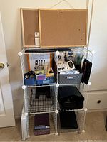 Full view of white wire shelving unit with two cork boards on top and assorted office supplies arranged in compartments including calculator, wrist pad, file trays, and storage bins.