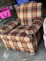 Front view of the brown plaid upholstered armchair showing the seat, armrests and backrest.