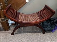 Side view of the curved wood bench showing cane seat and slatted wooden side panels