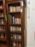 Full view of the wooden bookcase filled partially with books, showcasing the five shelves and the traditional crown molding design.