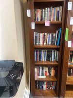 Full view of five wooden shelves filled with books, showing variety and condition of the collection