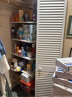 Wide view of five shelves filled with various household supplies including cleaners, tissue boxes, and personal care items.