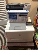 HP LaserJet printer with toner box and refill ink box on top