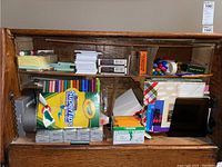 Shelf showing markers, colored pencils, greeting cards, envelopes, pens, index cards, and other stationery supplies.
