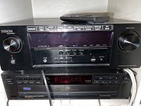 Denon AVR-S960H receiver stacked on top of Sony CD player with remote on top of receiver.
