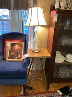 Crystal and brass lamp sitting on wood side table, with visible scratches on table top and turned legs.