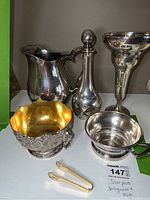 Group shot of six silver plated serving pieces on shelf