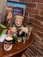 Photo showing seven Toby mugs with distinct faces arranged on a wooden surface near a brick wall.