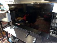 Front view of 55-inch flat-screen TV with remote controls on table