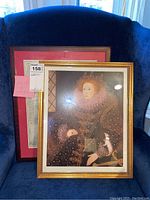 Two framed pieces displayed on blue chair: Queen Elizabeth I portrait and England & Wales map.