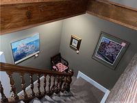 Photo of three visible framed wall art pieces hung on a stairwell wall, showing part of their placement and size in context.