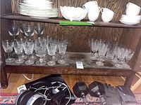 Shelf with multiple clear crystal glasses including Waterford and Gorham brands, assorted sizes and shapes.