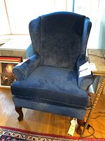 Front view of the blue velvet wing back chair showing the high back, winged sides, rolled arms and cushioned seat.