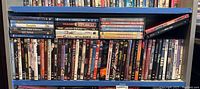 The full span of DVDs on shelf showing a mixed collection of movies and TV series cases in multiple rows and stacks.