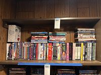 Wide shelf view showing multiple DVD cases arranged in rows on wooden shelves.