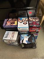 Photo showing multiple DVD box sets and collections piled on floor including comedy, music, and TV nostalgia series.