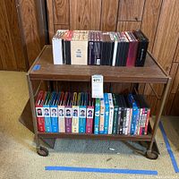 Photo of the rolling cart with DVDs on both shelves, showing the collection from a distance.