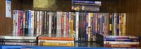 Photo showing a variety of DVDs stacked in a display shelf, titles include comedy and drama movies.