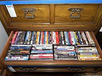 Wide view of wooden drawer filled with multiple rows of DVDs, showing a high quantity of cases packed tightly side by side.