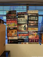 Photo showing a large stacked assortment of boxed DVD collections including comedy, children's favorites, and classic TV shows with colorful spines and titles visible.
