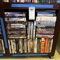 Wide view of multiple DVD stacks arranged on a shelf showing various titles and genres including comedy, musicals, horror, and classics.