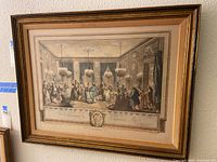 Front view of vintage framed engraving print showing ballroom scene with groups of figures in period attire under chandeliers.