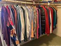 Wide shot showing a rack with various men's shirts, jackets, pullovers, sweatshirts, and blazers mostly in XL and XXL sizes in multiple colors and patterns.