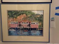 Photograph of the framed watercolor painting showing the Fisherman's Wharf and Sea Food Grotto pier scene with boats and hillside backdrop.