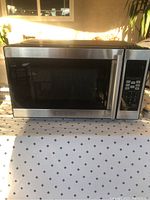 Closed microwave oven showing the front digital control panel and door with handle.