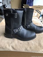 Side view of black women's leather boot showing decorative studded strap and side zipper