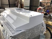 Side view of the white Broan range hood showing angular design and control knobs.