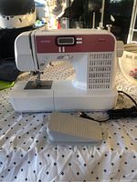 Front-left view of sewing machine with foot pedal and power cord